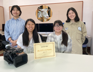 さがまちバンバンアワード2023で受賞した4名の学生と中央に賞状が置かれた写真。